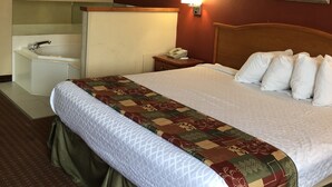 A hotel room with a bed, a bedside table with a lamp, a telephone, and a small table with a vase.