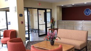 A lobby with a reception desk, a fire alarm, and a sign indicating an exit.