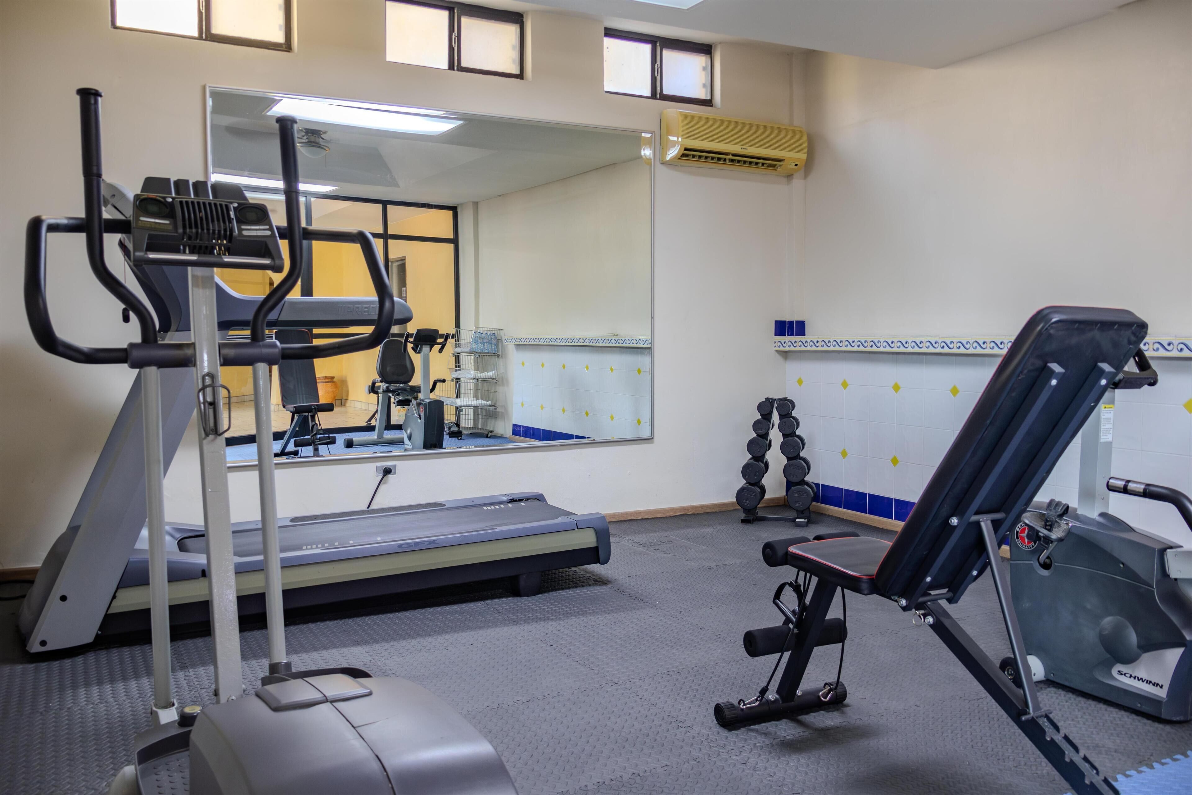 Une salle de sport équipée de tapis de course, de vélos elliptiques et d'appareils de musculation.