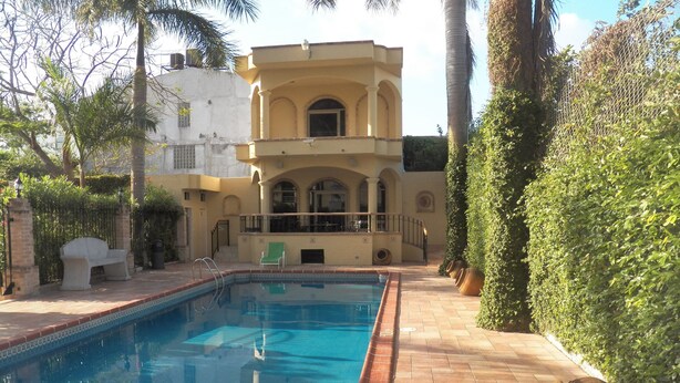 A swimming pool with lounge chairs, a tiled deck, and a building with a balcony in the background. - Best Western Hotel Plaza Matamoros (Matamoros)