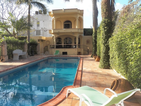 Una piscina al aire libre, sillones reclinables de piscina