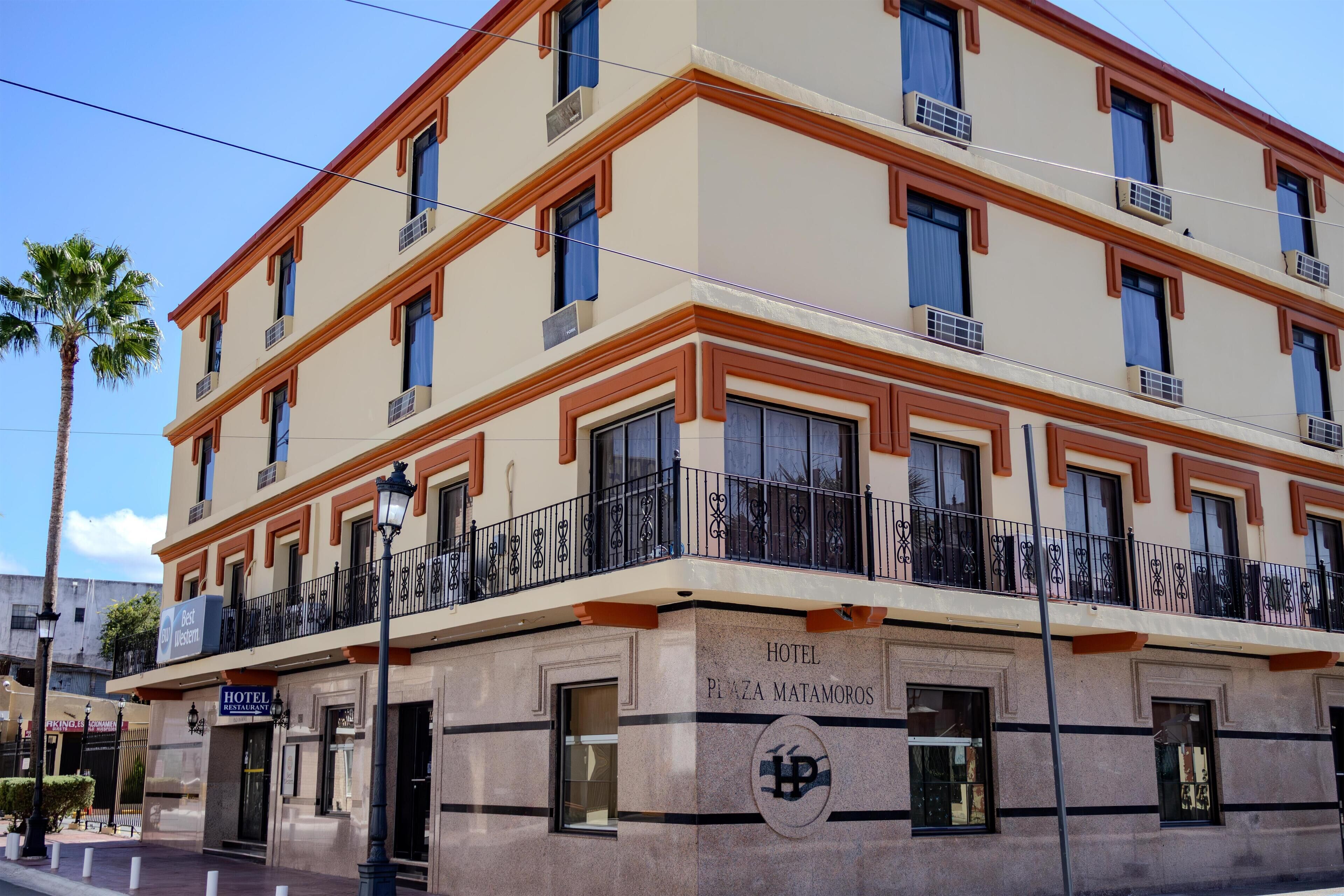 A multi-story hotel with a prominent 'HOTEL' sign on the facade, a balcony with decorative railings, and a 'Best Western' sign indicating the hotel chain.