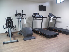 Un gimnasio con cinta de correr, elíptica y bicicleta estática.