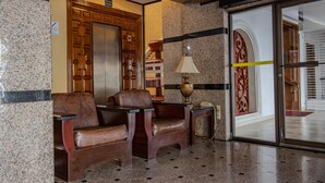 A lobby with two leather armchairs, a wooden elevator, a marble floor, and a glass door with a metal frame. - Best Western Hotel Plaza Matamoros (Matamoros)