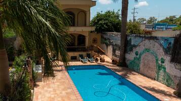 Una piscina al aire libre, sillones reclinables de piscina