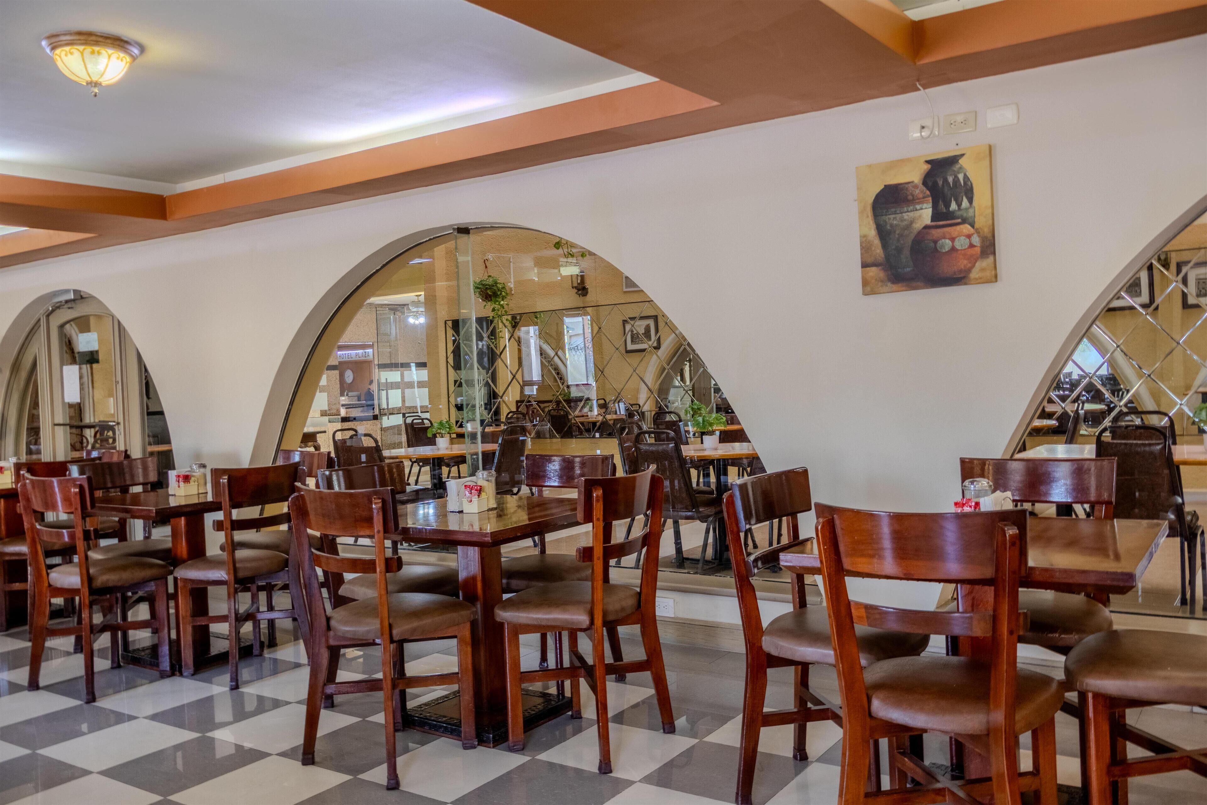 A restaurant with wooden tables and chairs, large arched windows, and a checkered floor.