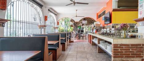 A restaurant with outdoor seating, a brick counter, and a ceiling fan.