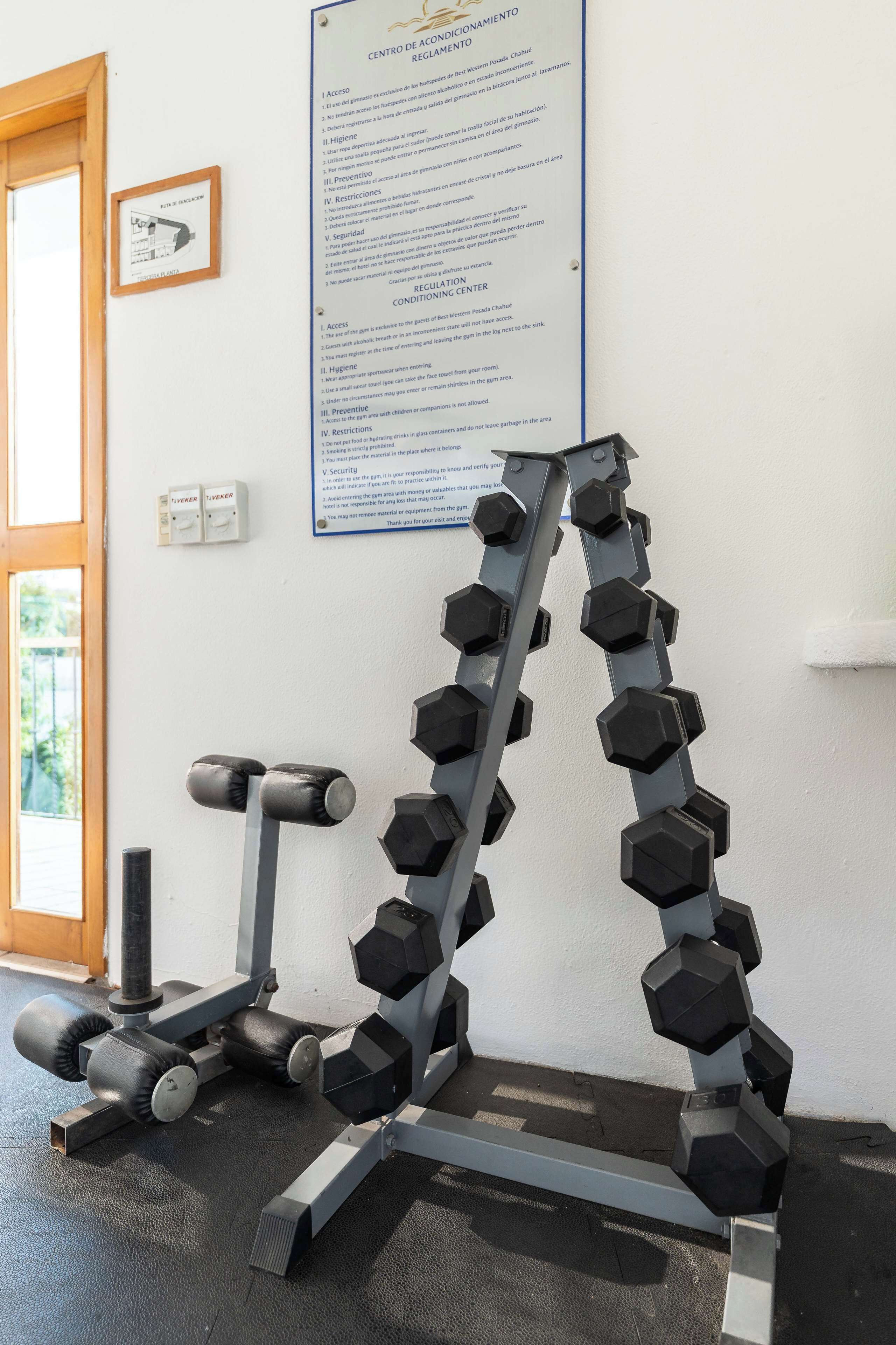 Ein Fitnessraum mit Hantelständer, einer Langhantelbank und einem Poster an der Wand.