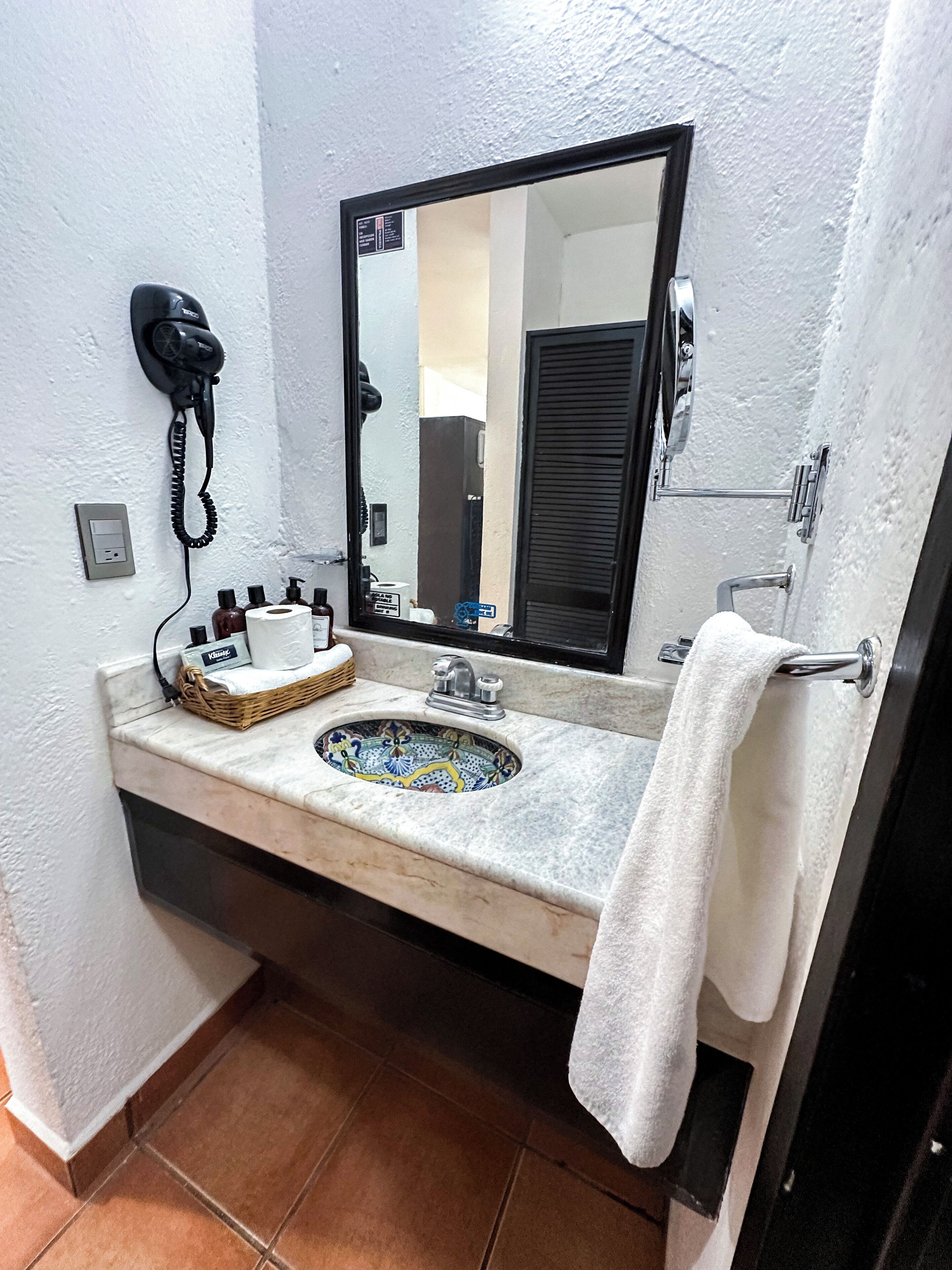 A bathroom with a sink, mirror, towel rack, and a telephone.
