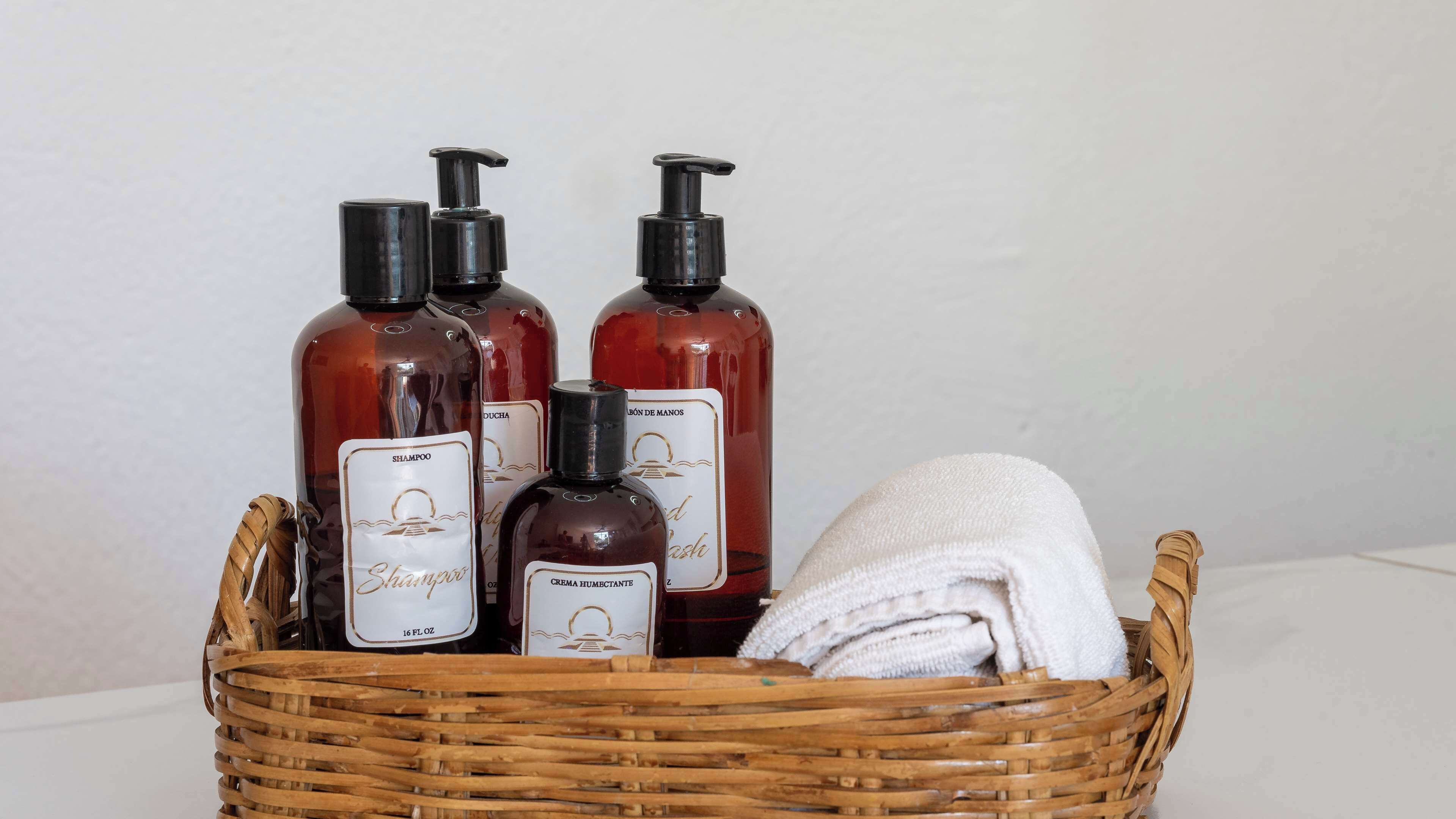 Un panier en osier contenant divers articles de toilette, notamment du shampoing, du gel douche et une serviette.