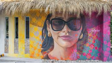 A mural with geometric patterns and a tropical thatched roof.