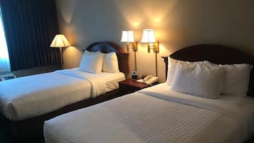 Une chambre d’hôtel avec deux lits, une table de chevet avec un téléphone et des lampes fixées au mur.