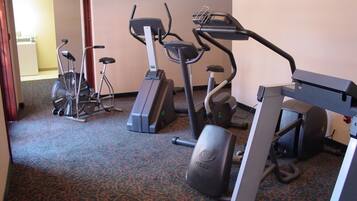 A hotel gym with stationary bikes, a treadmill, and a rowing machine.