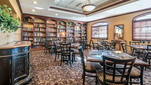 A library with bookshelves, tables, chairs, and a patterned carpet. - The Marx Hotel (Oneonta)