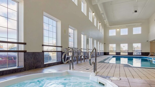 Una piscina interior con agua cristalina, rodeada de ventanas y un suelo de baldosas.