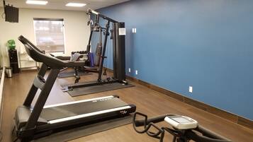 A gym with a treadmill, elliptical, and weight machines.