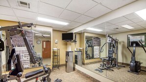 A gym with various exercise equipment, a water dispenser, and a mirror reflecting the equipment. - Quality Inn & Suites MidAmerica Industrial Park Area (Pryor)