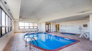 An indoor swimming pool with clear lane markings, a lifeguard chair, and a poolside table. - Quality Inn & Suites MidAmerica Industrial Park Area (Pryor)
