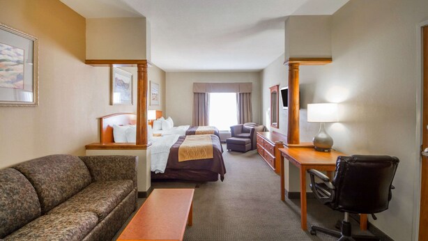 A hotel room with two beds, a sofa, a desk, a chair, and a lamp. - Quality Inn & Suites MidAmerica Industrial Park Area (Pryor)
