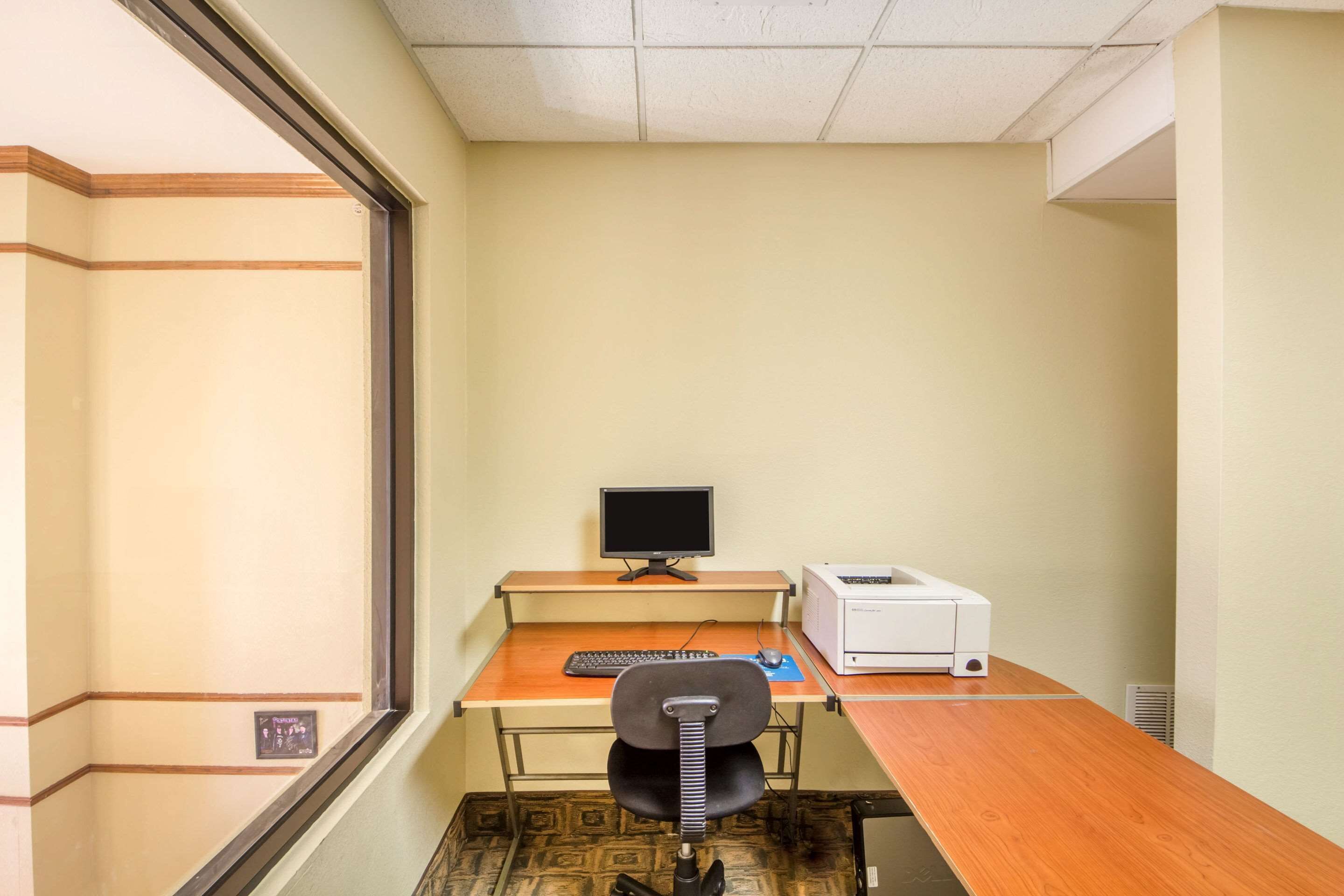 A small office with a desk, computer, printer, and chair.