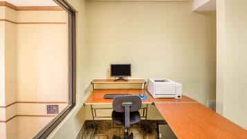 A small office with a desk, computer, printer, and chair.