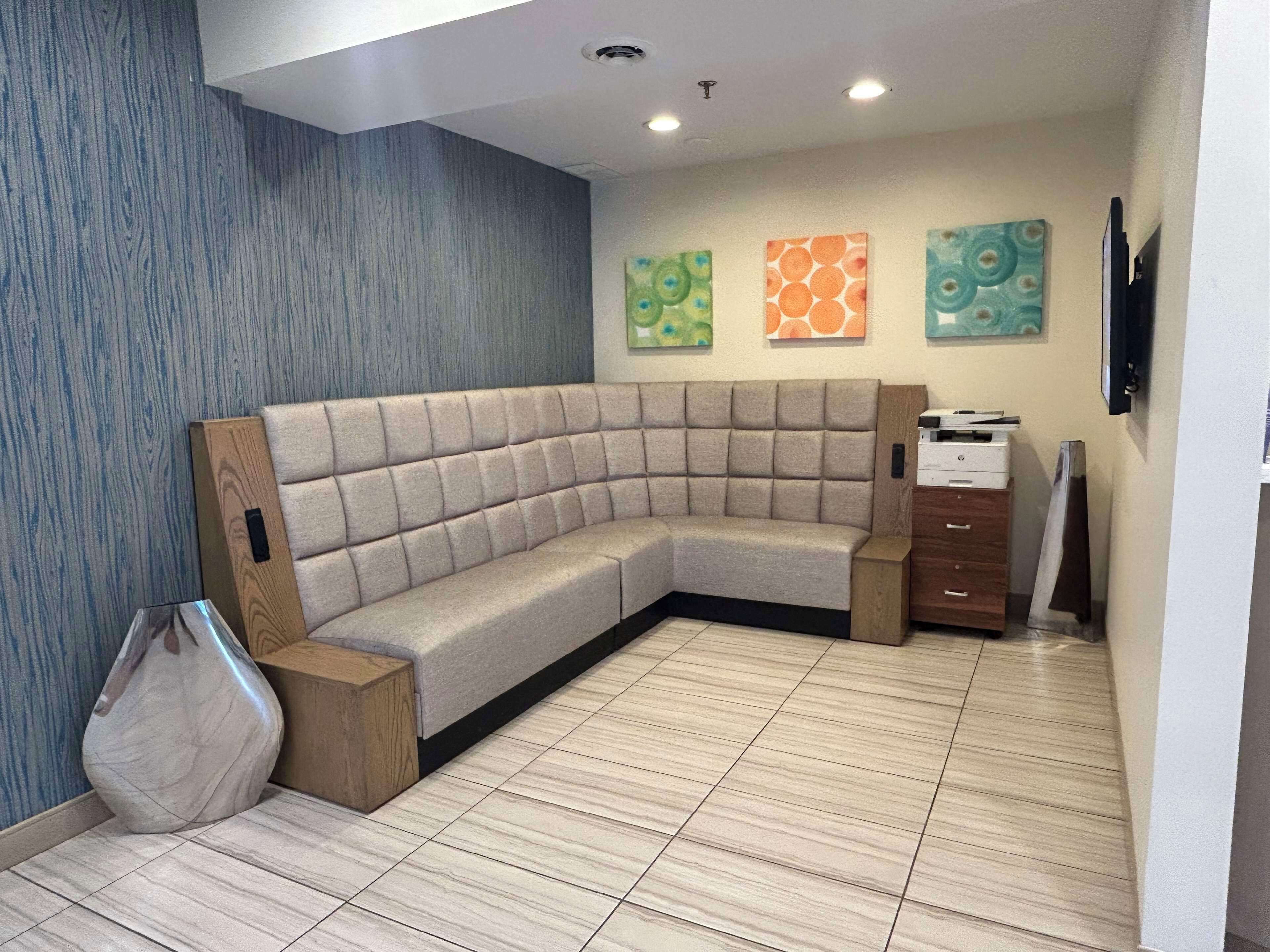 A modern room with a curved sofa, a wooden side table, and a printer.