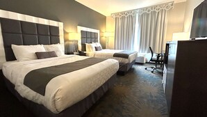 Une chambre d’hôtel avec deux lits, un bureau, une chaise et un téléviseur.