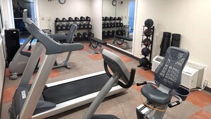 Une salle de sport équipée de tapis de course, de bancs de musculation et d’un porte-haltères.