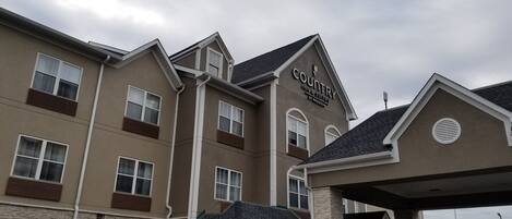 A Country Inn & Suites building with a stone facade, multiple windows, and a covered entrance area.