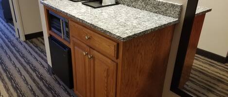 A compact kitchen with granite countertops, a built-in dishwasher, and wooden cabinets.