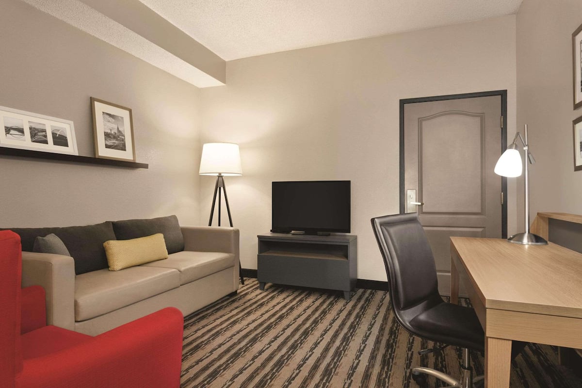 Habitación de hotel con sofá, televisor, escritorio, silla y lámpara.