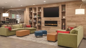 A modern living room with a large flat-screen TV, built-in shelving, and a fireplace.
