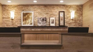 A reception area with a stone wall, framed artwork, and two wall-mounted light fixtures.