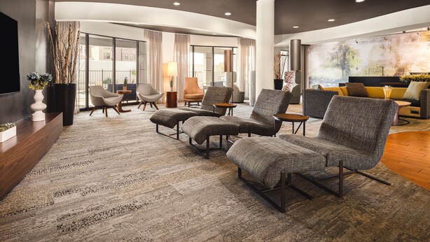 A modern lounge area with a large sectional sofa, armchairs, and a flat-screen TV. - Courtyard by Marriott El Paso Airport (El Paso)