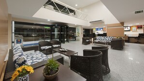 Eine geräumige Lobby mit hohen Decken, einer Glasfront und einer Sitzecke mit Korbmöbeln.
