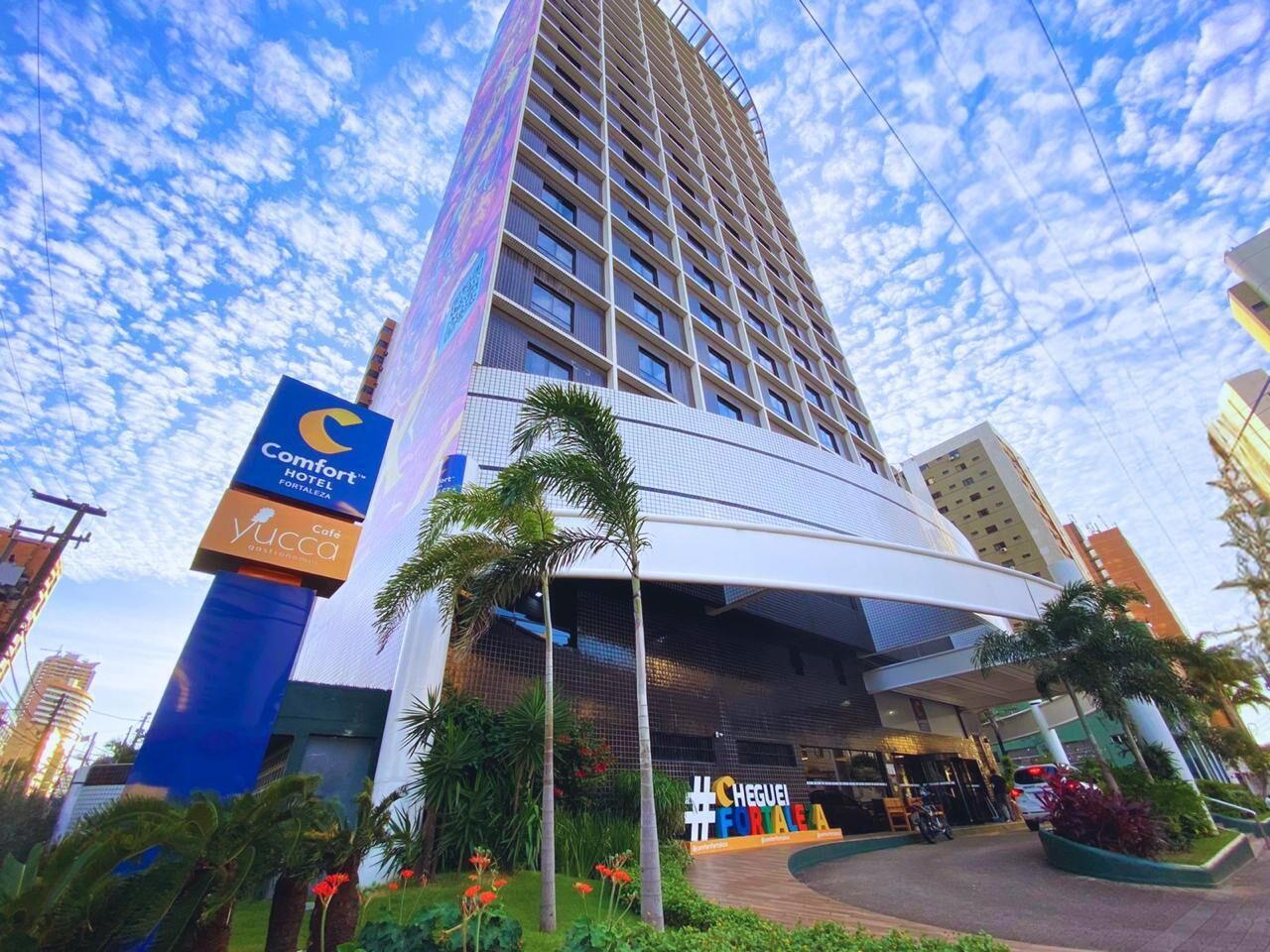 Un grand hôtel au design moderne, une enseigne bien visible indiquant qu’il s’agit du Comfort Hotel, et un espace extérieur bien entretenu avec des plantes.