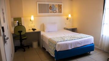 Una habitación de hotel con una cama, un escritorio, una silla, un teléfono y un cuadro en la pared.