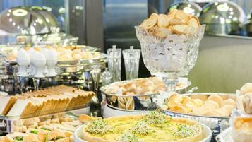 A buffet with various food items including sandwiches, pastries, and a quiche.