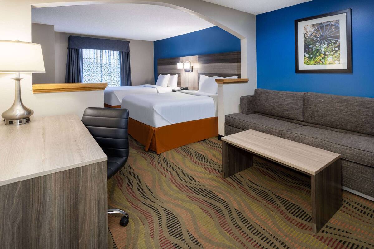 Een hotelkamer met twee bedden, een bureau, een bank en een kamerbreed tapijt met patroon.