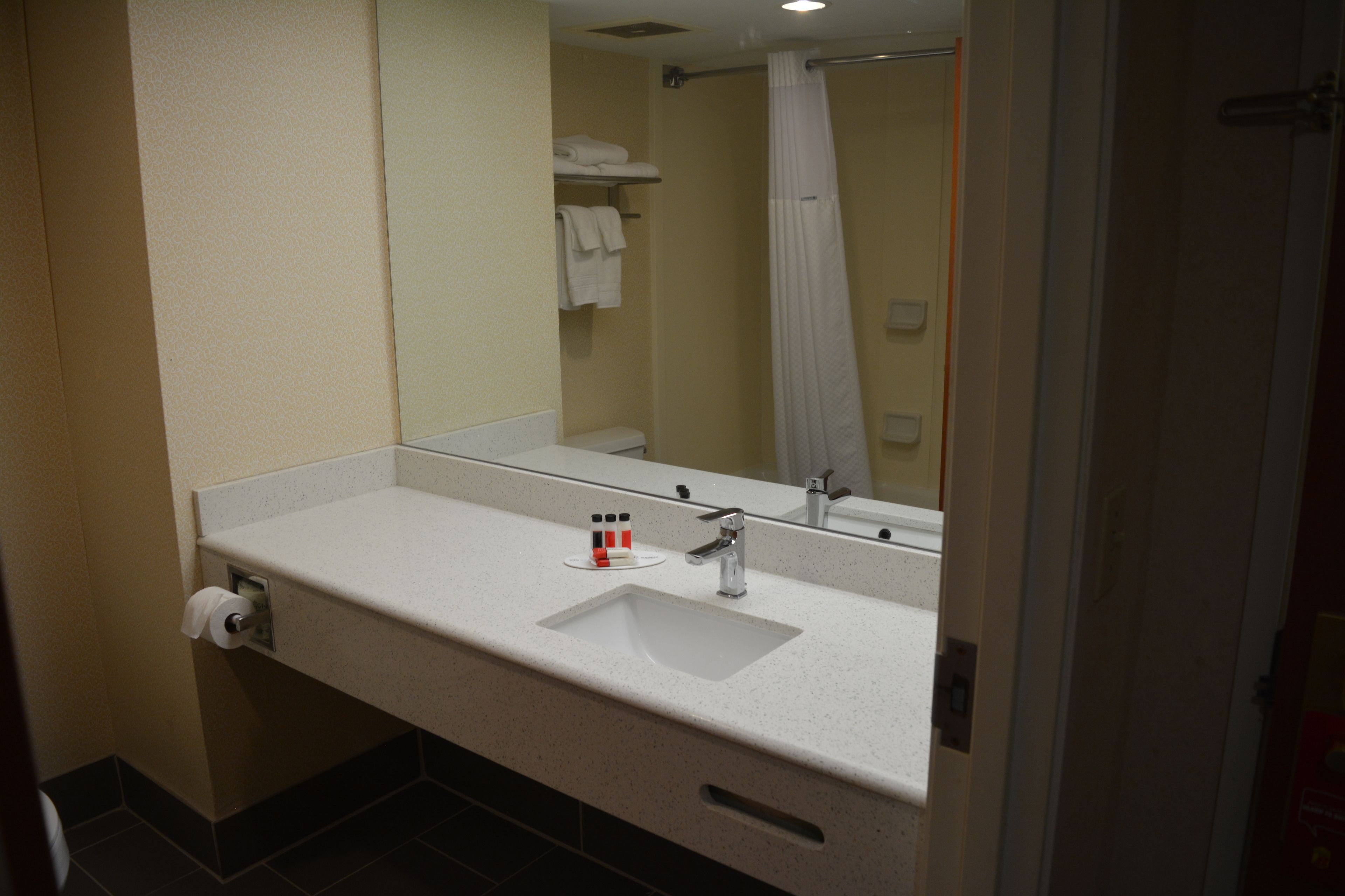 Une salle de bain avec un lavabo blanc, un miroir et un rideau de douche.