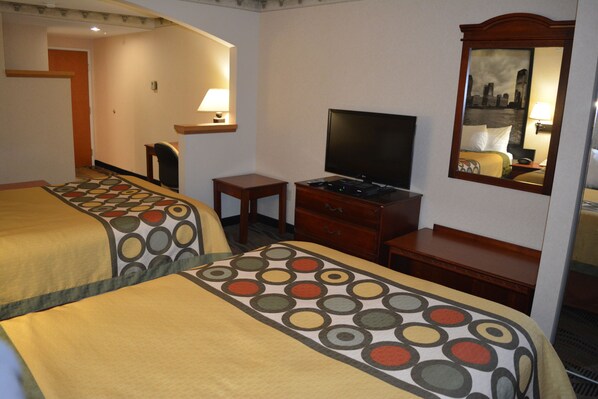Habitación de hotel con dos camas, un televisor, un escritorio y un espejo.