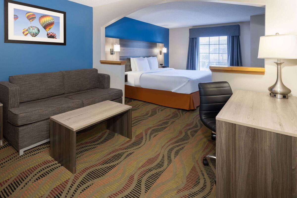 Een hotelkamer met een bed, een slaapbank, een bureau en een stoel.
