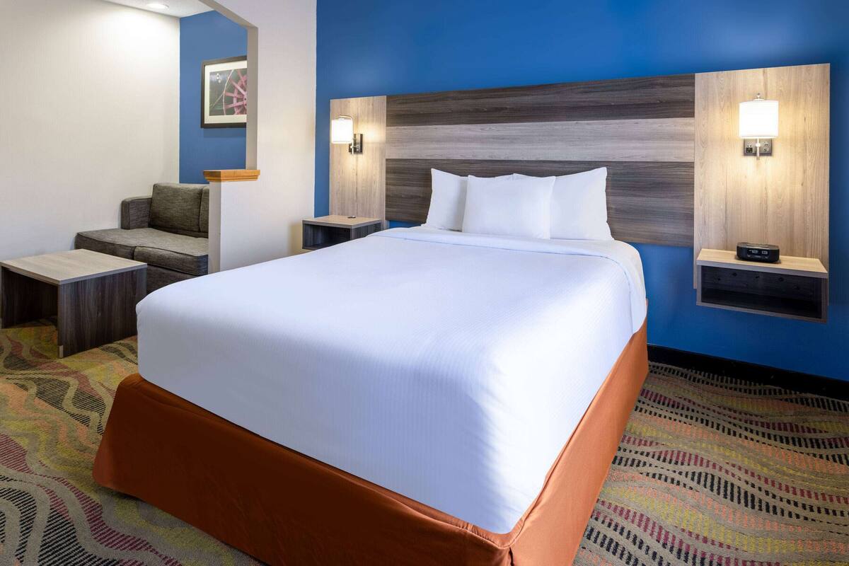 Een hotelkamer met een groot bed, een bank, twee nachtkastjes en een wandlamp.