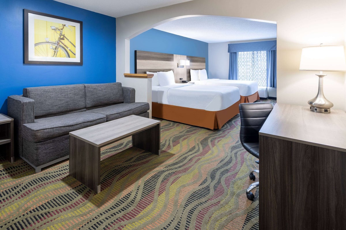 Een hotelkamer met een bank, een bed, een bureau en een kamerbreed tapijt met dessin.