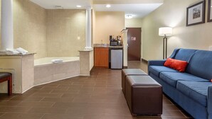 A hotel room with a bathtub, a sofa, a coffee machine, and a refrigerator. - Comfort Suites Newark - Harrison (Newark)