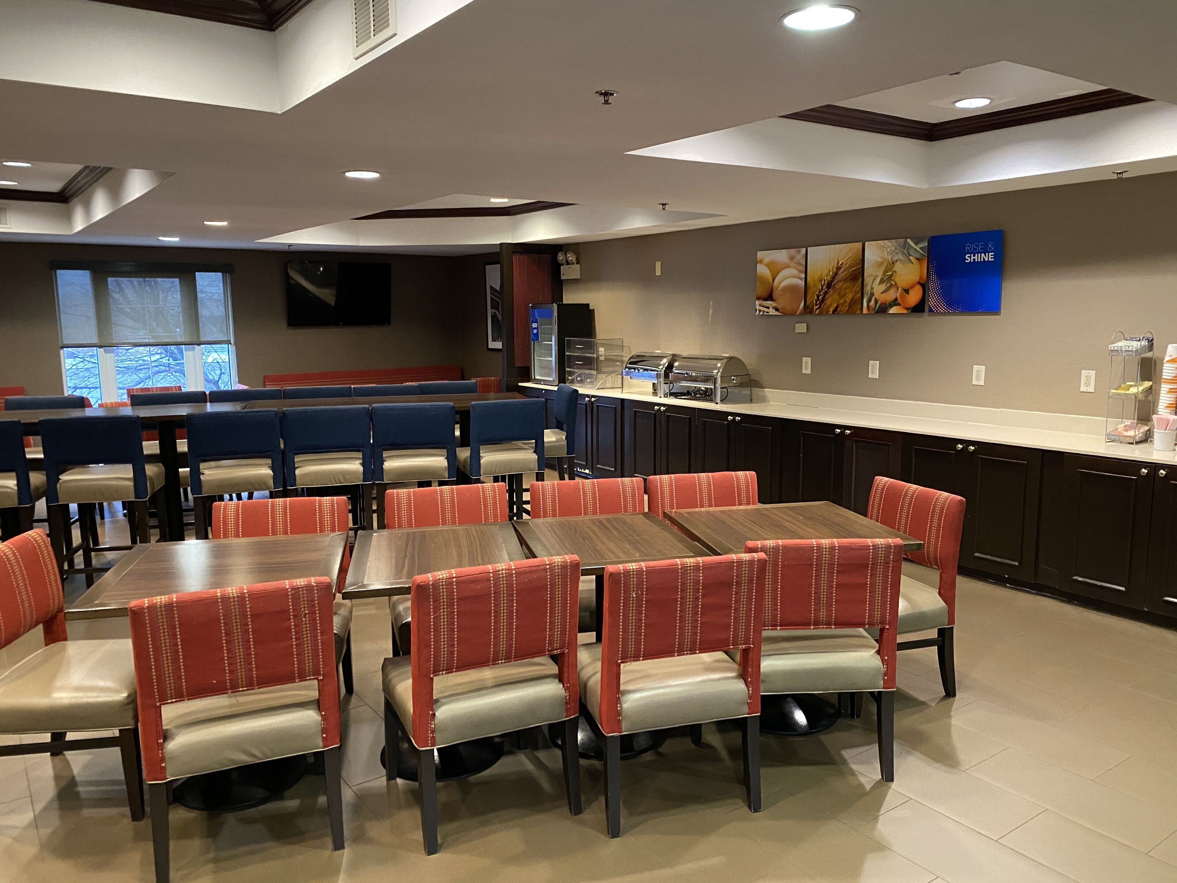 A restaurant with booths and tables, a kitchen area, and a large window with a view.