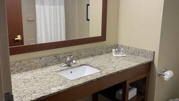 Un baño con lavamanos de encimera de granito, un espejo y un perchero para toallas.