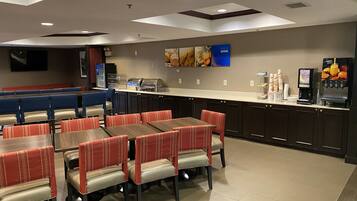A restaurant with booths and tables, a counter with a coffee machine, and wall decorations.