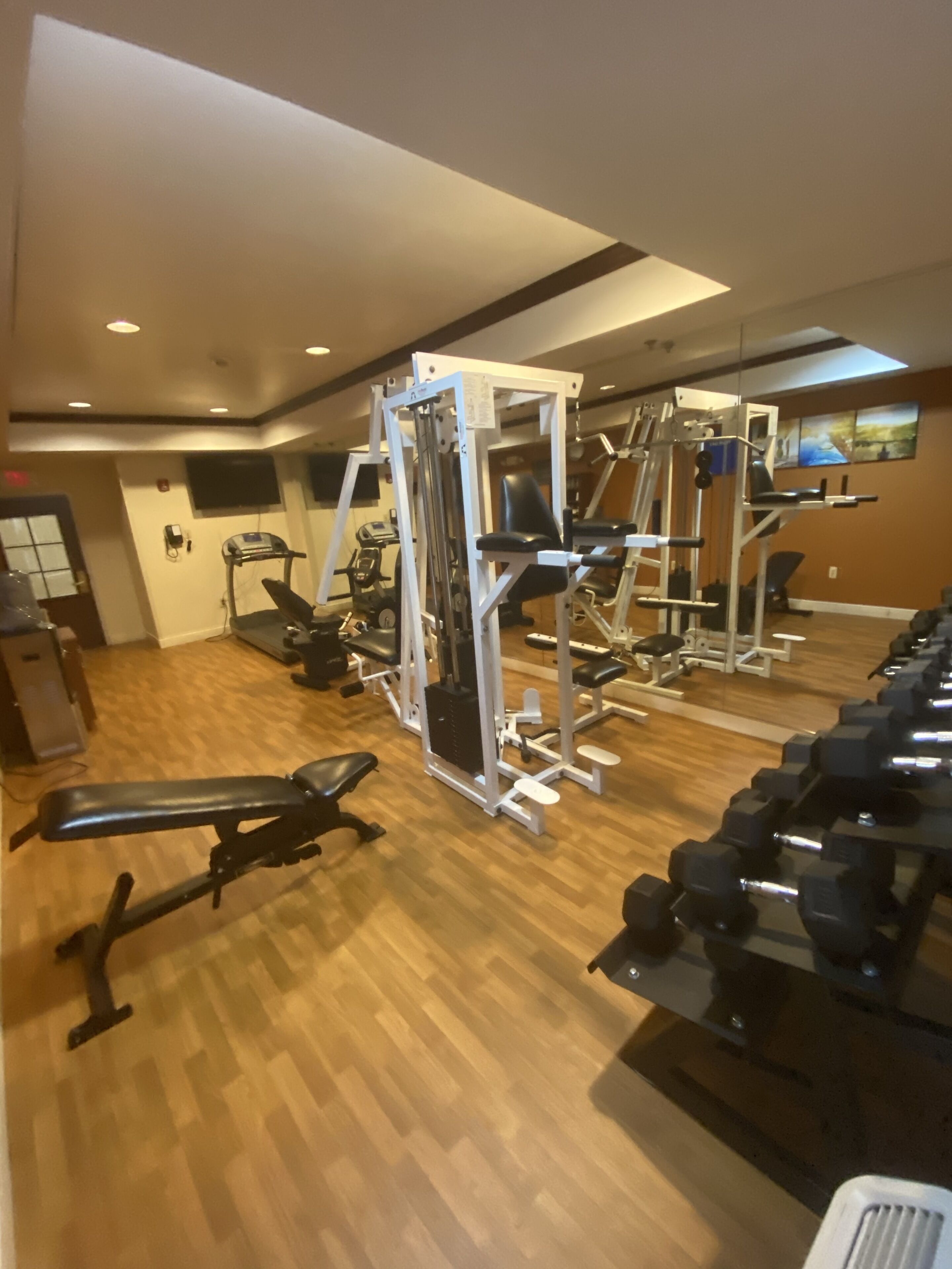 Une salle de sport équipée de divers appareils d’exercice, notamment des haltères, des bancs et des machines de musculation.
