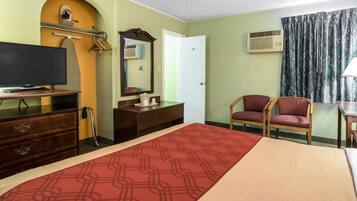 A hotel room with a bed, a TV, a dresser, a mirror, a chair, and a window with curtains.